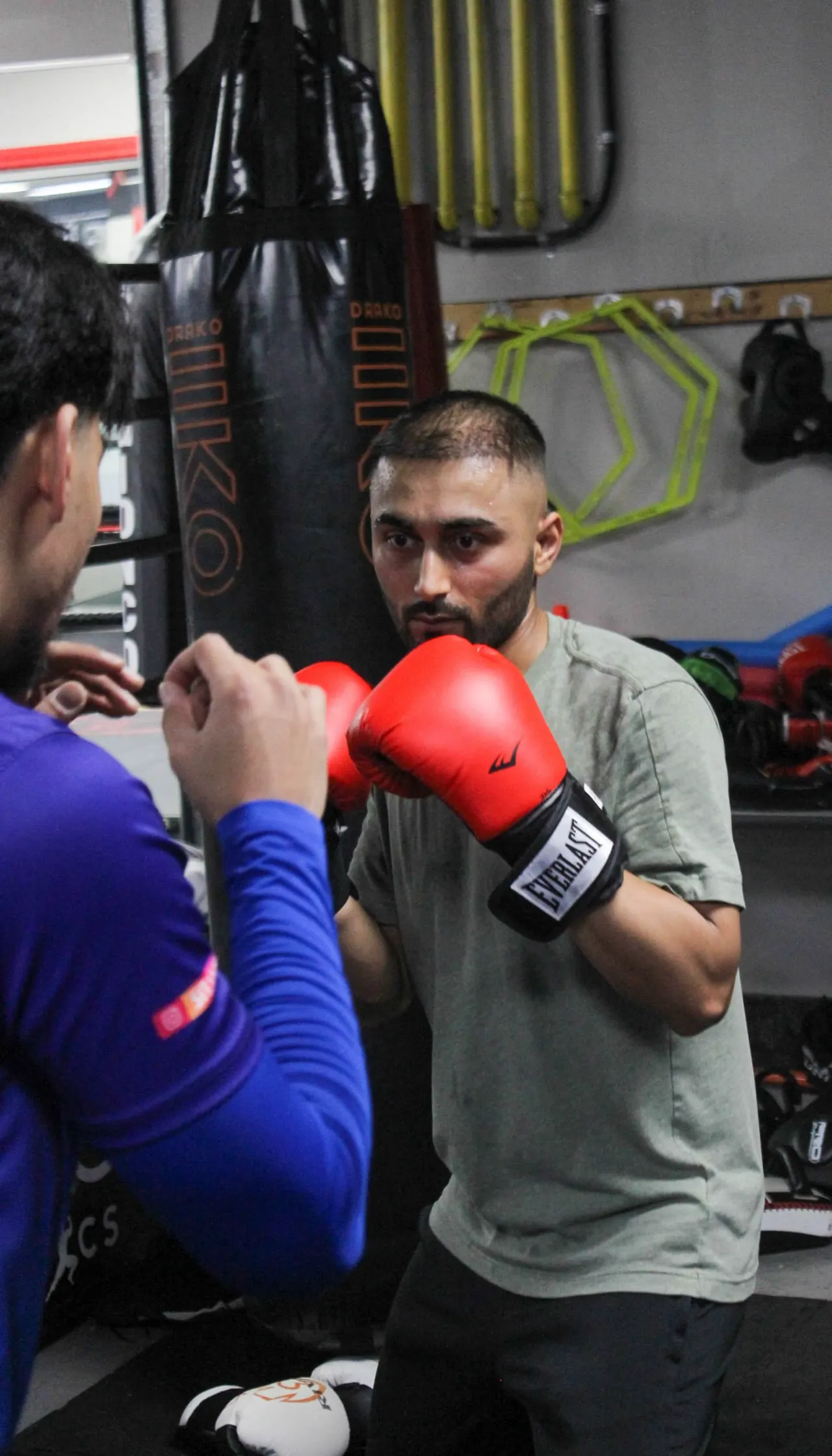 Justin holding pads for a student drilling guards in red gloves