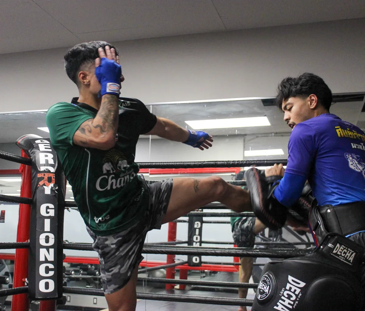 A student landing a kick on Justin's pads during live padwork